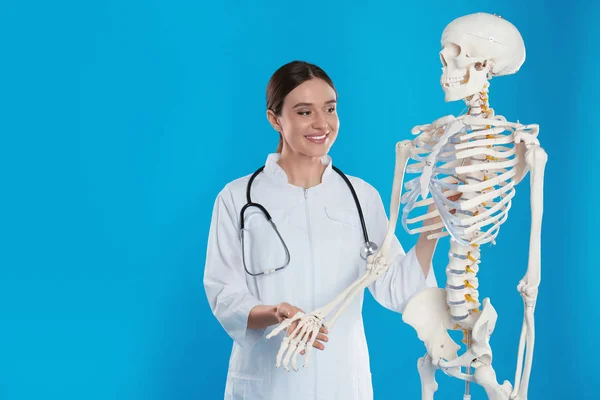 Female Orthopedist Human Skeleton Model Blue Background — Stockfoto