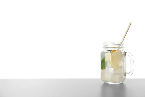 Delicious lemonade in mason jar on grey table against white background. Space for text