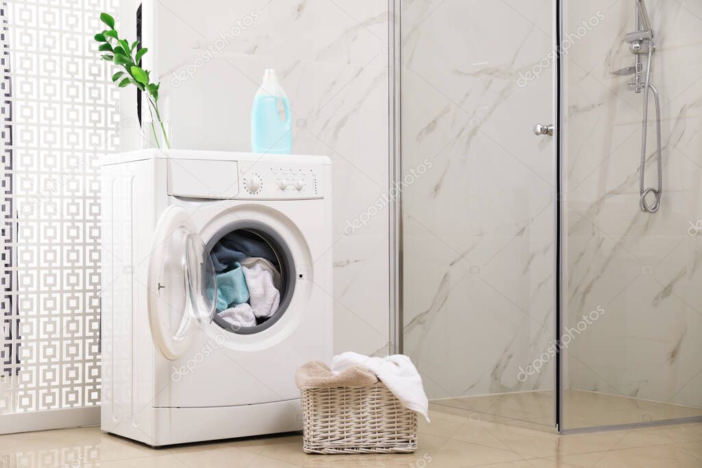 Modern washing machine with towels in bathroom