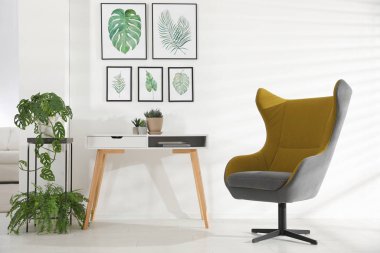 Rahat koltuk ve tropikal yaprak resimleriyle süslü bir oda.