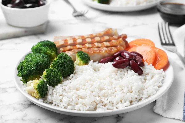 Delicious rice with beans and meat served on white marble table, closeup