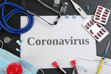 Siyah masanın üzerinde CORONAVIRUS, steteskop ve ilaç kelimeleriyle düz kompozisyon