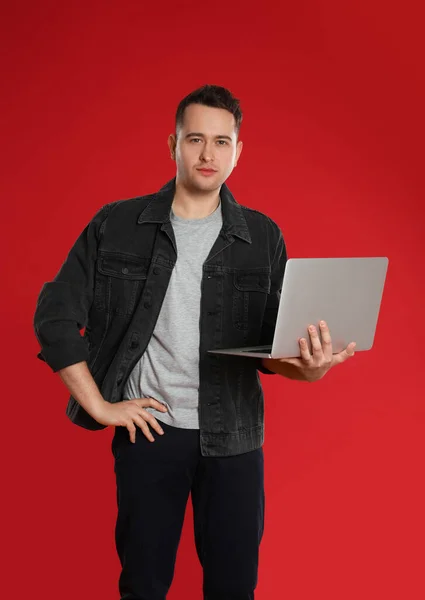 Kırmızı Arka Planda Dizüstü Bilgisayarı Tutan Genç Adam — Stok fotoğraf