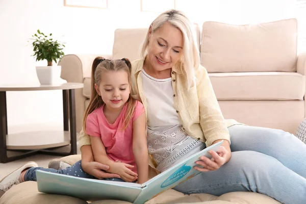 一个成熟的女人和她的小孙女一起在家里看书 — 图库照片