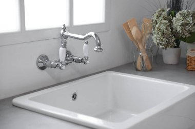 Yeni seramik lavabosu ve musluğu olan mutfak tezgahı.