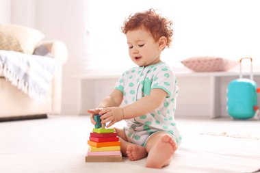Evde yerde oyuncaklarla oynayan şirin bir çocuk.