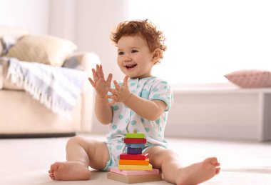 Evde yerde oyuncaklarla oynayan şirin bir çocuk.