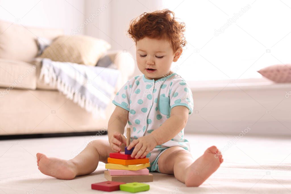 Cute little child playing with toy on floor at home