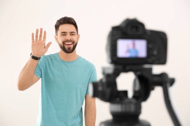 Genç blogcu beyaz arkaplana karşı kameraya video kaydediyor