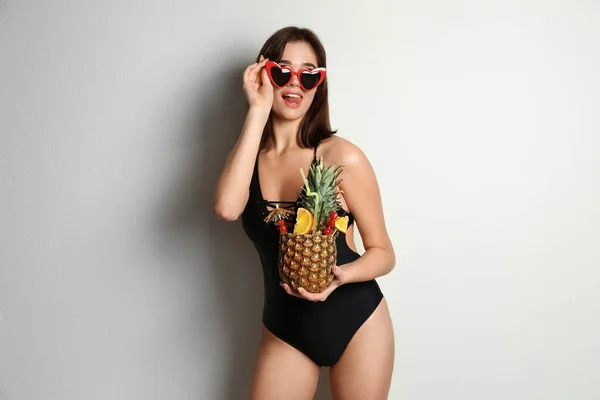 Schöne Frau Eleganten Badeanzug Mit Tropischem Cocktail Auf Hellgrauem Hintergrund — Stockfoto