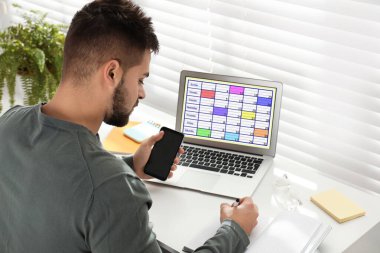 Dizüstü bilgisayarında takvim uygulamasıyla programını planlayan genç bir adam.