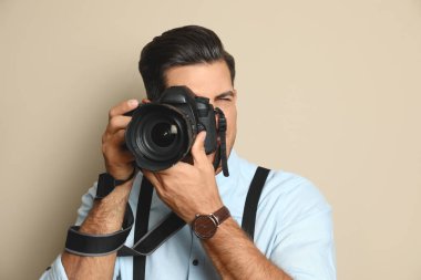 Stüdyoda bej arka plan üzerinde çalışan profesyonel fotoğrafçı.