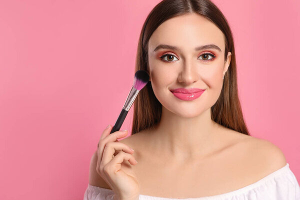 Beauty blogger doing makeup on pink background