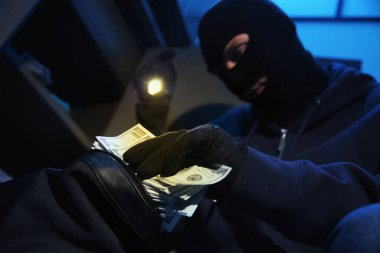 Hırsız, gece vakti çelik kasadan para alıyor, yakın plan.