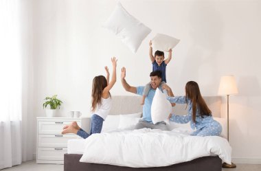 Mutlu aile yatak odasında yastık savaşı yapıyor.