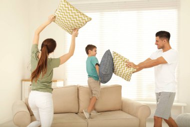 Mutlu aile oturma odasında yastık savaşı yapıyor.