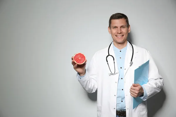 熟したグレープフルーツと薄い灰色の背景にクリップボードを持つ栄養士 テキストのスペース — ストック写真