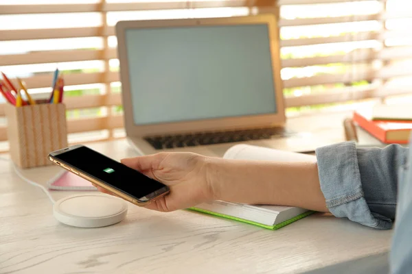 Donna Che Mette Cellulare Sul Caricabatterie Wireless Tavolo Legno Bianco — Foto Stock