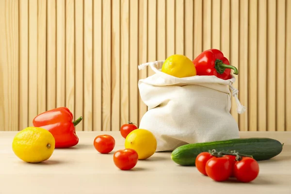 Cotton eco bag with vegetables and fruits on wooden table