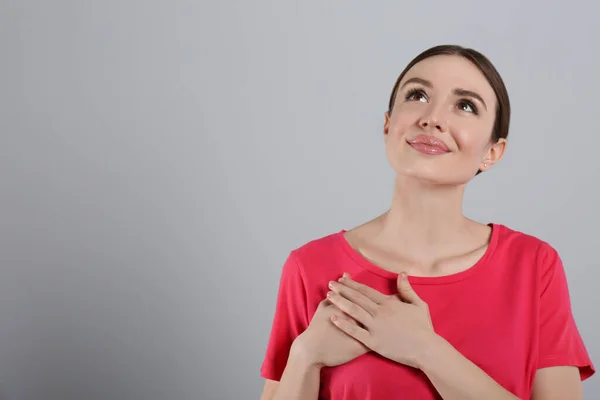 Mooie Dankbare Vrouw Met Handen Borst Tegen Lichtgrijze Achtergrond Ruimte — Stockfoto