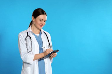 Steteskoplu ve mavi arka planda panosu olan bir doktor. Metin için boşluk