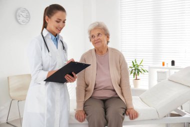 Modern ofisteki kıdemli hastayı muayene eden doktor.