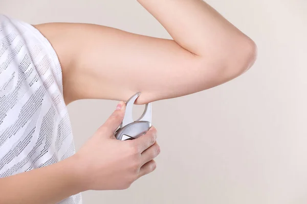 Mujer Joven Midiendo Grasa Corporal Con Pinza Sobre Fondo Beige — Foto de Stock