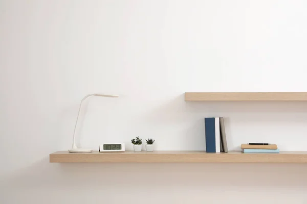 Wooden shelves with books and decorative elements on light wall