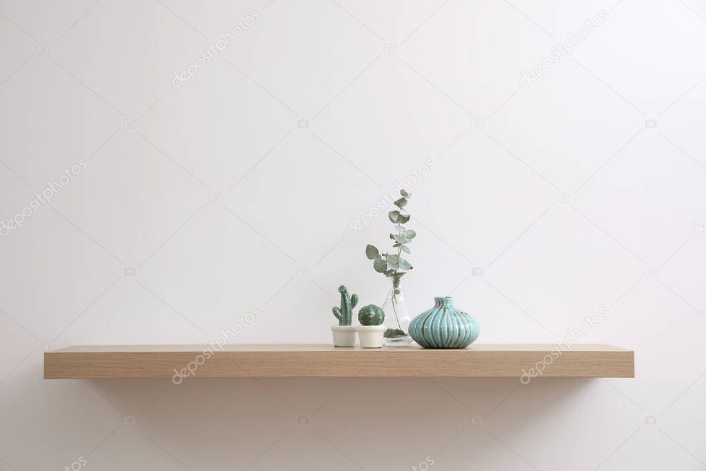Wooden shelf with decorative elements on light wall