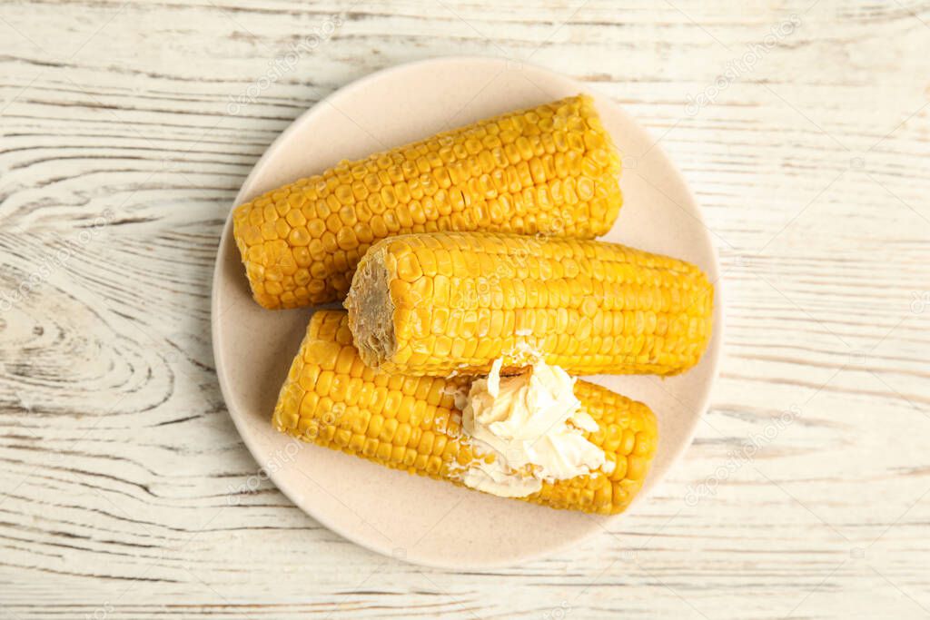 Delicious boiled corn with butter on white wooden table, top view