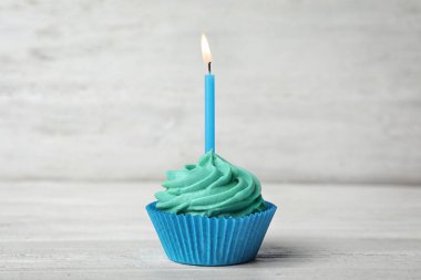 Beyaz ahşap masada kremalı ve yanan mumlu nefis bir doğum günü pastası.
