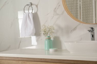 Banyo içinde çiçekli vazo ve yumuşak havlu.