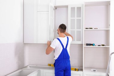 İşçi mutfağa tornavidayla dolap kapısı kuruyor