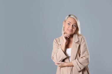 Gri arka planda güzel olgun bir kadının portresi. Metin için boşluk