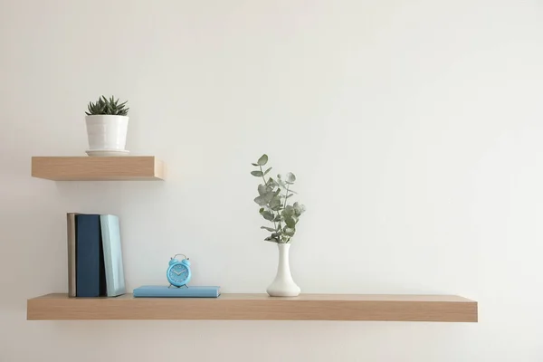 美しい植物 目覚まし時計と光の壁に本を持つ木製の棚 — ストック写真
