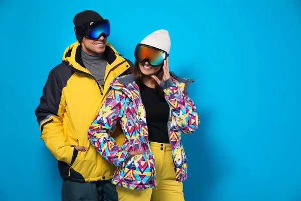 Couple wearing stylish winter sport clothes on light blue background