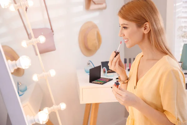 ドレッシングルームで鏡の近くに化粧を適用する美しい若い女性 — ストック写真