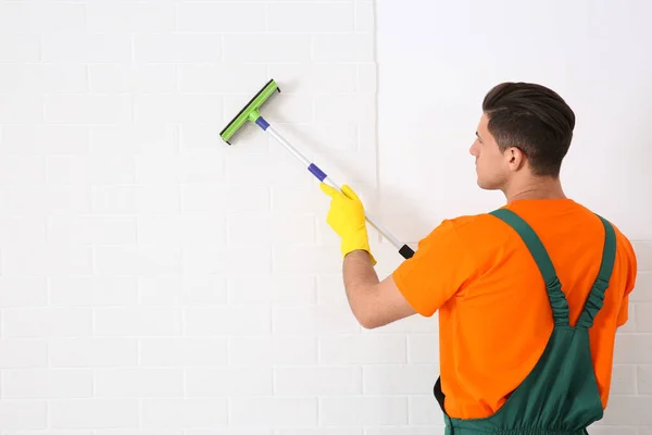 Profissional Zelador Limpeza Parede Tijolo Branco Com Rodo Dentro Casa — Fotografia de Stock