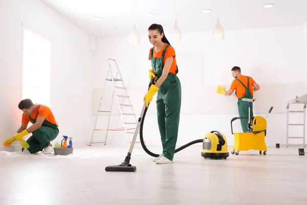 Team of professional janitors cleaning room after renovation