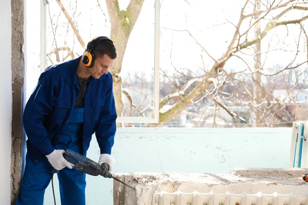 Worker using rotary drill hammer for window installation indoors