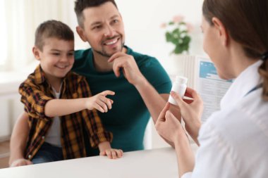 Father and son visiting pediatrician. Doctor working with little patient in hospital clipart