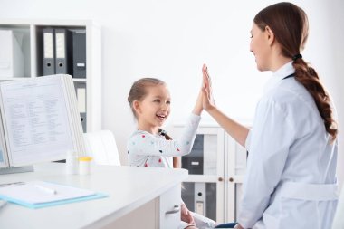 Çocuk doktoru küçük bir hastayla klinikte çalışıyor.