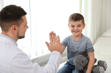 Çocuk doktoru küçük bir hastayla klinikte çalışıyor.