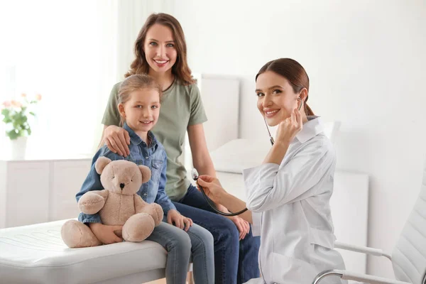 Mother and daughter visiting pediatrician. Doctor examining little patient with stethoscope in hospital