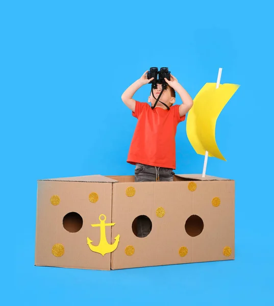 可爱的小孩在浅蓝色背景下玩双筒望远镜和纸船 — 图库照片