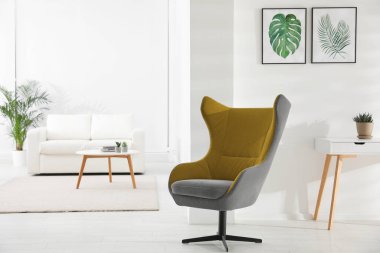 Rahat koltuk ve tropikal yaprak resimleriyle süslü bir oda.