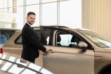 Galerideki yeni arabanın yanındaki genç satıcı.
