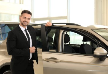 Galerideki yeni arabanın yanındaki genç satıcı.