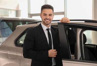 Galerideki yeni arabanın yanındaki genç satıcı.
