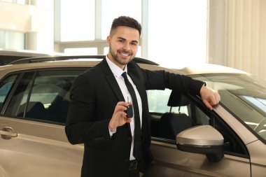 Araba galerisinde anahtarı olan genç bir satıcı.